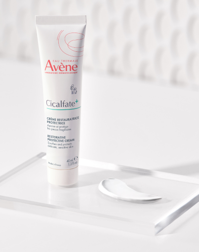 A tube of Avène Cicalfate+ restorative cream on a clear tray, with a smear of cream beside it.