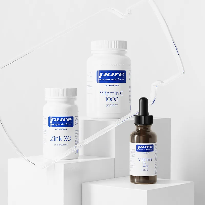 Vitamin supplements on white blocks, including Zink 30, Vitamin C 1000, and liquid Vitamin D3.